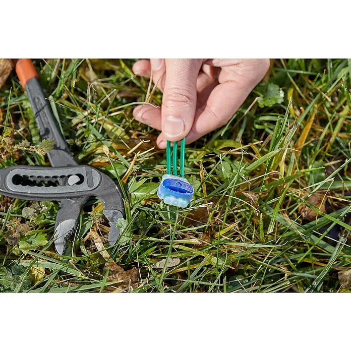 Gardena Conector clip para robot cortacésped R40LI - Específico para: Robot cortacésped Gardena - Un conector de cable 3M azul sujetado en una mano, con unos alicates al lado, que permite una unión segura de cables.