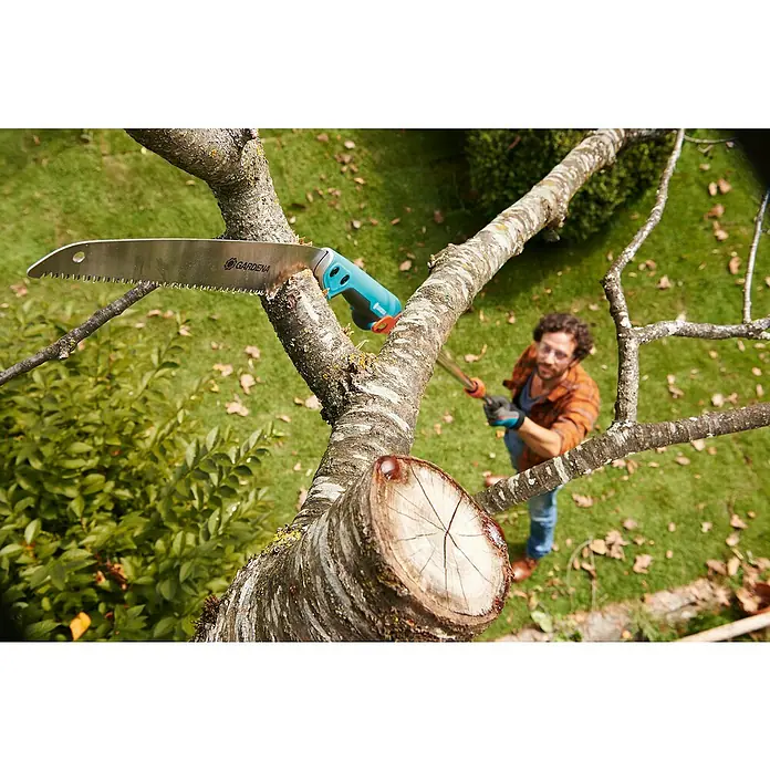Gardena Combisystem Hand-Astsäge 300PP - Länge: 514 mm, Kunststoff, Silber, Türkis - Nahaufnahme einer Gardena Astsäge, die an einem Baum befestigt ist, mit einem Mann im Hintergrund, ideal für Baumschnittarbeiten.