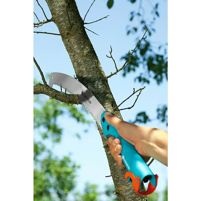 Gardena Combisystem Sierra de podar manual 300PP - Largo: 556 mm, Plástico, Plateado, Turquesa - Serrucho de podar Gardena en acción: Un árbol está siendo cortado con una sierra curva con mango azul para quitar ramas.