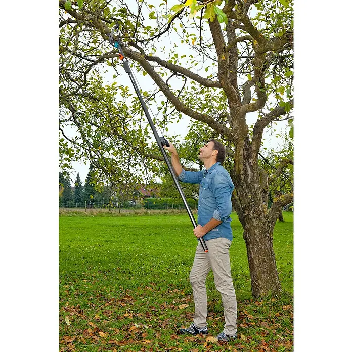 Gardena Combisystem Cortarramas de jardín - Grosor de rama máx.: 35 mm, Mango tipo D con resistente cable de tracción, sistema de guardado de cable (sin enredos) y fijación de cable - Hombre utilizando una podadora de mango largo para cortar ramas de un árbol. La podadora es una herramienta útil para jardinería.
