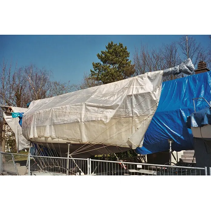 Seilflechter Lona acuática - L x An: 4 x 8 m, Gramaje: 250 g/m² - Un velero está cubierto con una lona blanca y una lona azul para la temporada de invierno, protegiéndolo del clima.