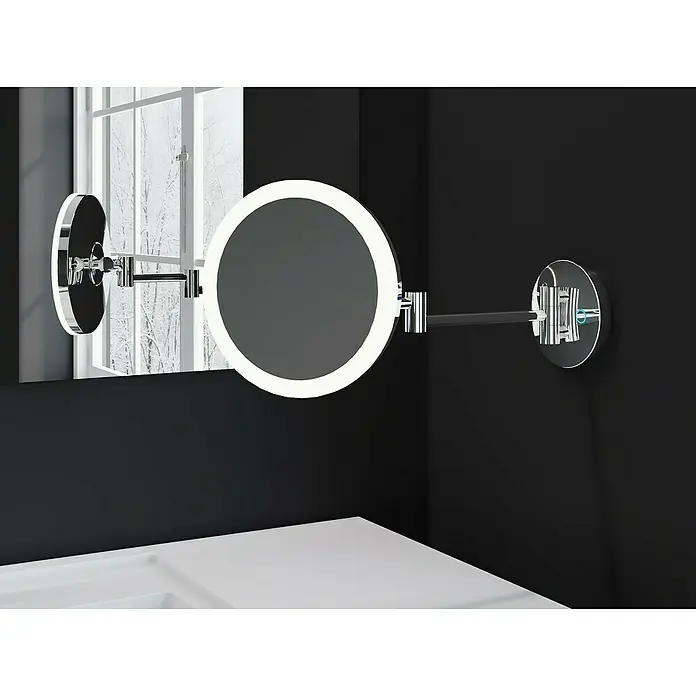 Cosmic Espejo cosmético de pared Essentials - Cromo - Un espejo cosmético iluminado con brazo cromado está montado en una pared de baño negra, proporcionando una solución elegante para el cuidado diario.