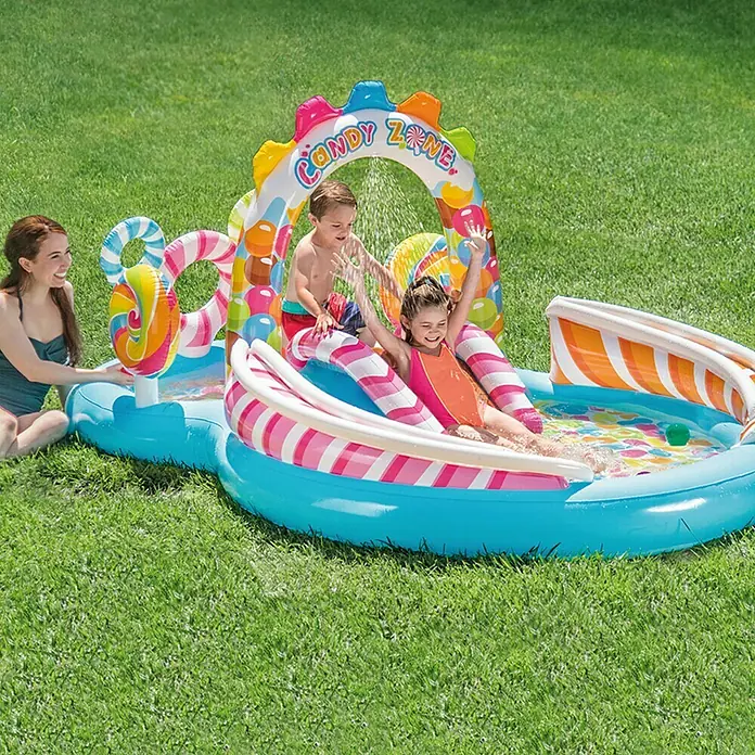 Intex Planschbecken Candy Zone Play CenterL x B x H: 295 x 191 x 130 cm, Mehrfarbig - Ein aufblasbares Planschbecken "Candy Zone" mit Rutsche, einer Frau und zwei Kindern im Garten.