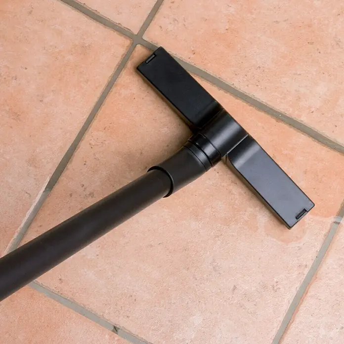 Ubbink Teichschlammsauger VacuProCleaner Maxi1.250 W - 1.400 W, Tankvolumen: 35 l - Nahaufnahme des schwarzen Düsenaufsatzes eines Staubsaugers auf einem beigen Fliesenboden.