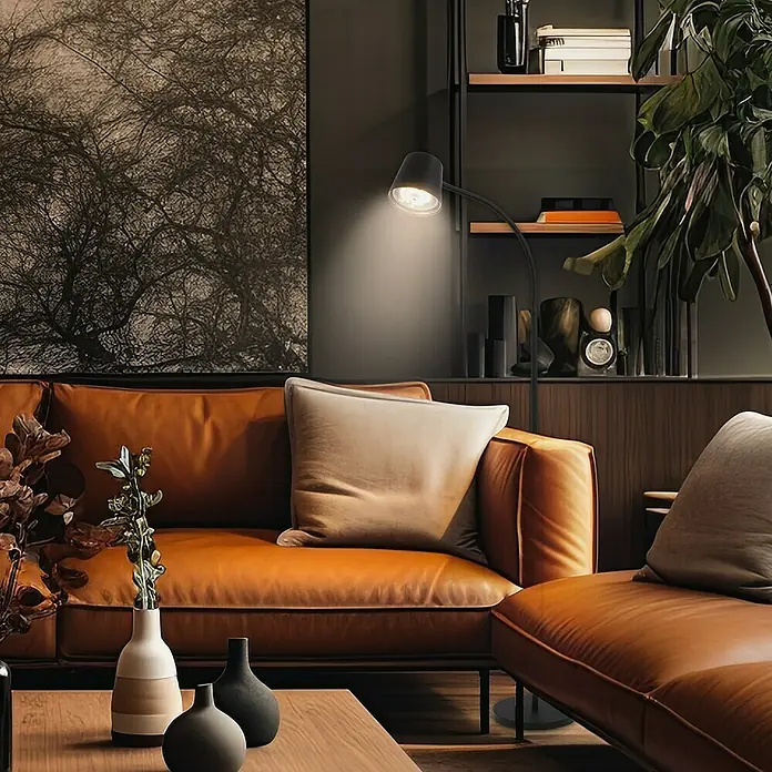 Brilo Akku-Stehleuchte Cielo - Warmweiß, 5,5 W, IP20 - Ein modernes Wohnzimmer mit einem braunen Ledersofa, einem Couchtisch und einer eleganten Stehlampe, die das Ambiente beleuchtet.