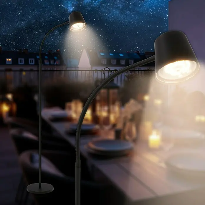 Brilo Akku-Stehleuchte Cielo - Warmweiß, 5,5 W, IP20 - Zwei moderne schwarze Stehlampen beleuchten einen Tisch im Freien unter einem sternenklaren Nachthimmel.