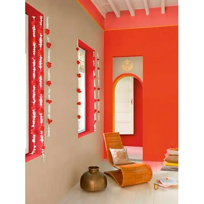 Bruguer Colores del Mundo Pintura para paredes - Nepal beige intermedio, Mate, 4 l - Habitación acogedora con paredes naranjas, silla de madera y ventanas con guirnaldas florales. Ambiente alegre y luminoso.