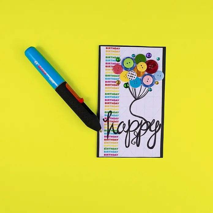 Bosch Akku-Heißklebestift Gluey - Farbe: Lagoon Blue - Kreative Grußkarte zum Geburtstag mit bunten Knöpfen und einem BOSCH Gluey Heißklebestift in Blau, ideal für DIY-Projekte und Scrapbooking.