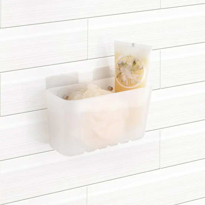 Tatay Standard Cesta de baño - L x An x Al: 8,5 x 20 x 11 cm, Transparente - Primer plano de una cesta de ducha con una esponja de baño y gel de ducha en una pared blanca texturizada. Almacenamiento práctico para el baño.