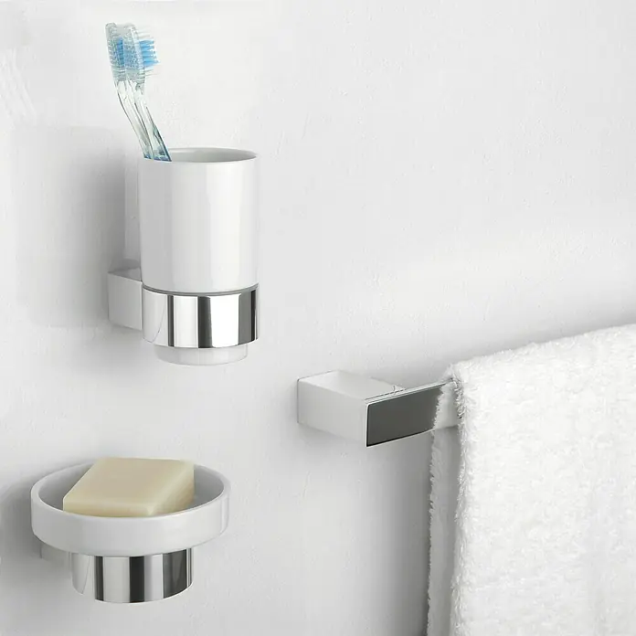 Tatay Oslo Toallero de barra - Ancho: 61 cm, Cromo - Primer plano de un set de baño blanco y cromado que incluye una jabonera, un vaso con cepillos de dientes y un toallero con una toalla.