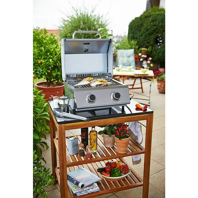 Grillstar Barbacoa de gas de mesa Atlanta 200 T - Superficie de la parrilla (An x Pr): 40 x 33 cm, 4,4 kW, Número de quemadores: 2 - Una parrilla compacta sobre un carro de madera, con ingredientes y verduras listos para una deliciosa comida al aire libre.