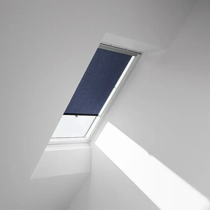 Velux Dachfensterrollo Haltekrallen RHL MK00 9050 - Farbe: Dunkelblau - 9050, Farbe Schiene: Aluminium, Manuell - Ein Dachfenster mit einem heruntergelassenen, marineblauen Rollo in einem hellen, modernen Raum.