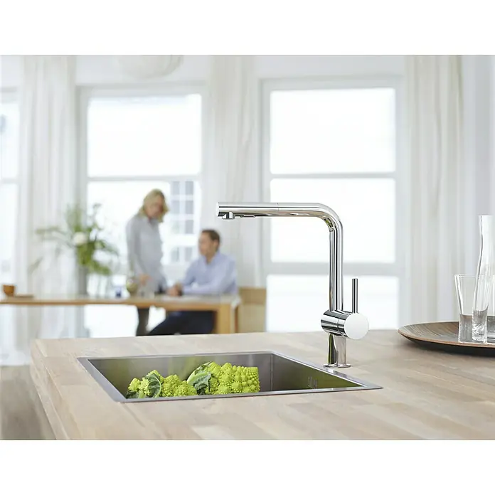 Grohe Spültischarmatur Minta - L-Auslauf, Chrom, Glänzend, Anzahl Strahlarten: 2 Stk. - Eine glänzende Küchenarmatur mit geradem Auslauf und seitlichem Hebel steht im Fokus, mit Gemüse im Spülbecken.