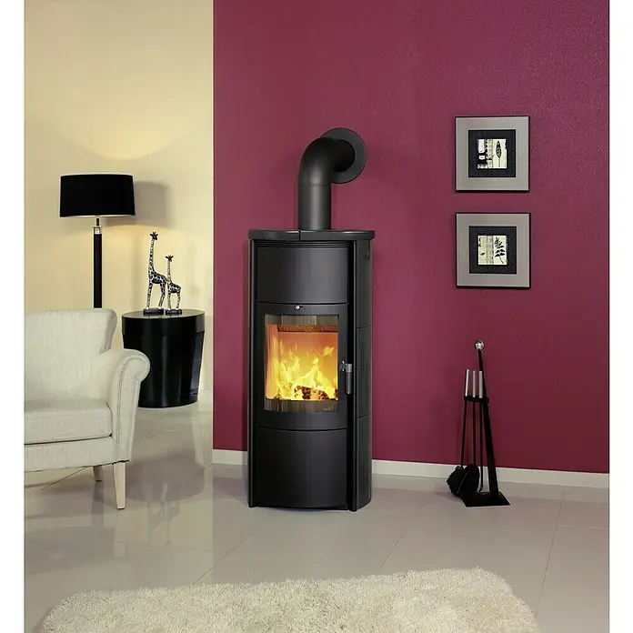 Hark Kaminofen Keno ECOplus - 5 kW, Raumheizvermögen: 138 m³, Material Verkleidung: Keramik, Meteor-Schwarz - Kaminofen mit Flammen, stehend auf einem weißen Teppich in einem stilvollen Wohnzimmer mit moderner Einrichtung.