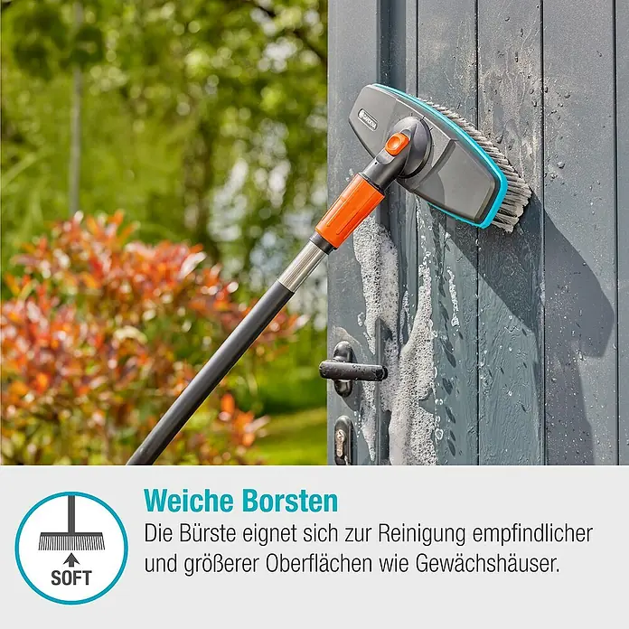 Gardena Cleansystem Waschbürsten-Set - Länge Stiel: 90 cm, Wasserführend - Das Bild zeigt eine Gardena Waschbürste mit Teleskopstiel, die eine graue Tür mit Seife reinigt.