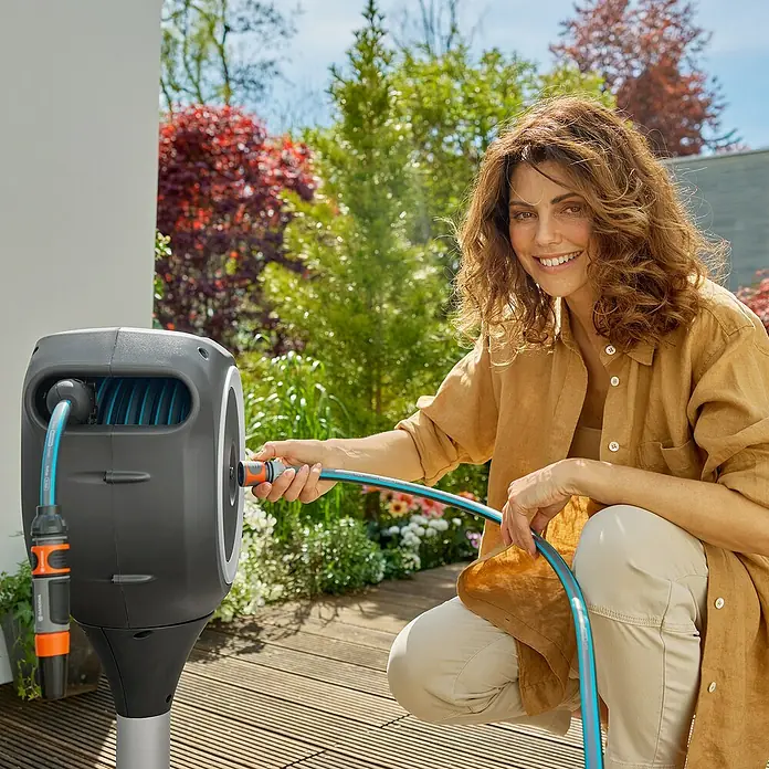 Gardena Schlauchbox Roll-Up S - Schlauchlänge: 15 m, 360 ° drehbar - Frau benutzt eine Gardena Wand-Schlauchbox 35 roll-up automatic für die Gartenbewässerung. Praktische und komfortable Gartenarbeit mit diesem Produkt.