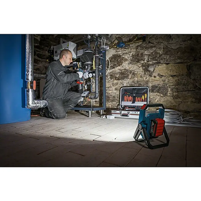 Bosch Professional AMPShare 18V LED-Akkustrahler GLI 18V-1900 - 18 V, Ohne Akku, Lichtstrom: 1.900 lm - Ein Handwerker arbeitet im Keller mit einem Bosch Akku-Baustrahler. Der Strahler beleuchtet den Arbeitsbereich und die Werkzeugkiste.