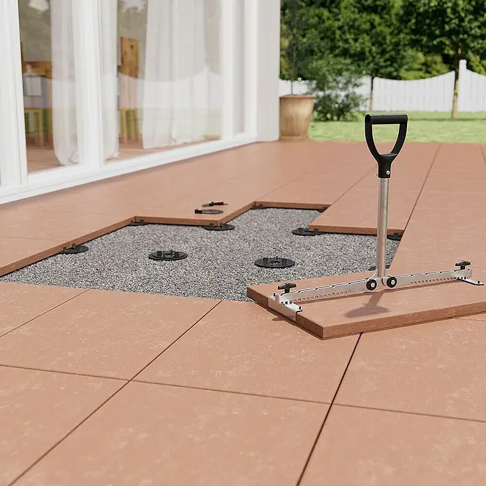 Langfit Kieslager - 10 Stk., Kunststoff, Ganze Scheibe - Terrassenbau mit Werkzeug: Das Bild zeigt die Verlegung von Terrassenplatten mit einem speziellen Werkzeug auf Unterkonstruktion aus Kies.