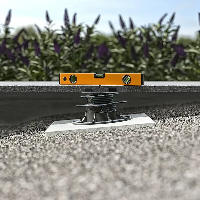 Langfit Stelzlager XL - 5 Stk., Höhenverstellung: 75 mm - 195 mm - Ein grauer Terrassenboden auf verstellbaren Stelzlagern mit einer orangefarbenen Wasserwaage zur Ausrichtung.