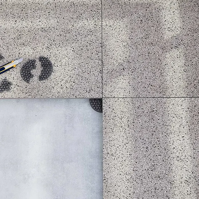 Langfit Plattenlager - 10 Stk., Kunststoff, Fugenbreite 3 mm - Ein detailliertes Bild von Terrassenplatten, teilweise mit Werkzeug und Abstandshaltern, ideal für Bau- und Renovierungsprojekte.