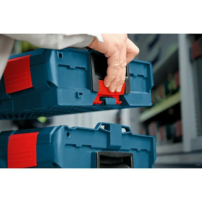 Bosch Professional Systemkoffer L-Boxx 136 - L x B x H: 357 x 442 x 151 mm, ABS - Detailaufnahme von Bosch Werkzeugkoffern mit roten Verschlüssen, die von einer Hand bedient werden. Fokus auf das Stapelsystem.