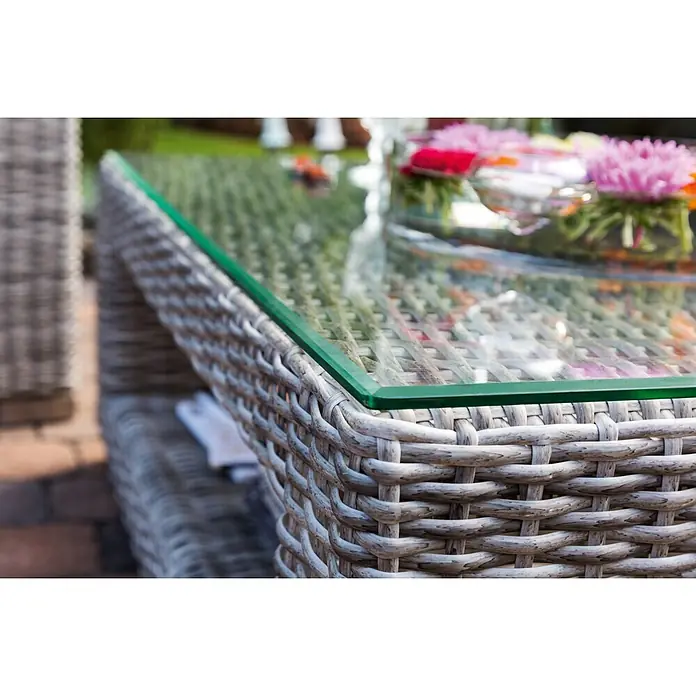 Sunfun Pauline Loungemöbel-Set XXL - 4 -tlg., Polyrattan, Bambusgrau/Anthrazit - Nahaufnahme eines grauen Rattantisches mit einer durchsichtigen Glasplatte und Blumen als Dekoration, perfekt für den Außenbereich.