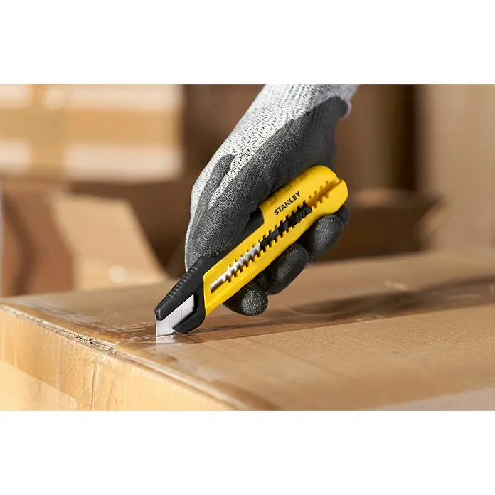 Stanley Cuchillo cúter STHT10489-0 - Plástico, Amarillo/Negro - Un cúter Stanley amarillo corta un paquete de cartón, sujetado por una mano con un guante protector.