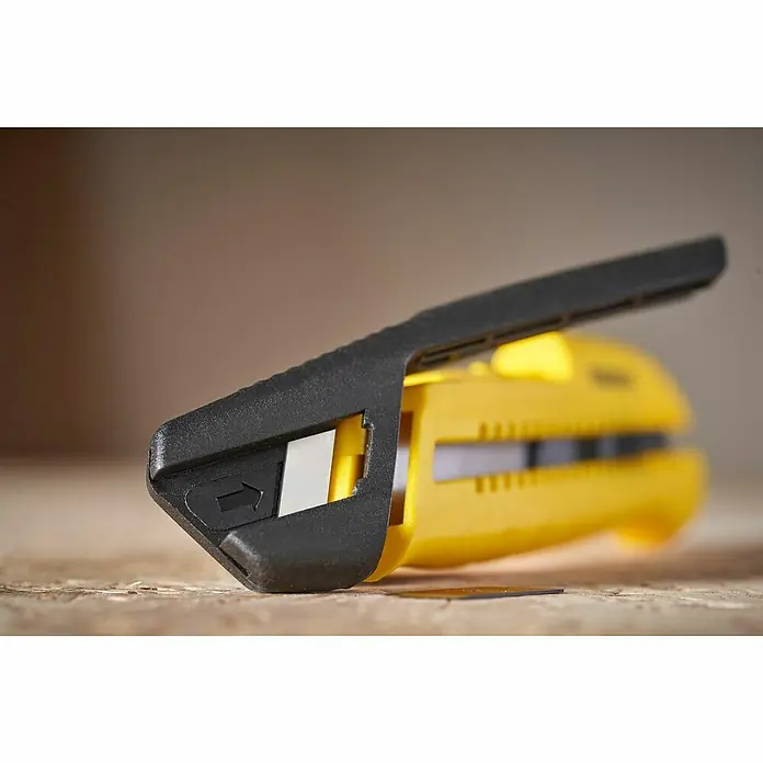 Stanley Cuchillo cúter STHT10489-0 - Plástico, Amarillo/Negro - Primer plano de un cúter Stanley amarillo con mango negro sobre una superficie de madera, revelando una hoja afilada.