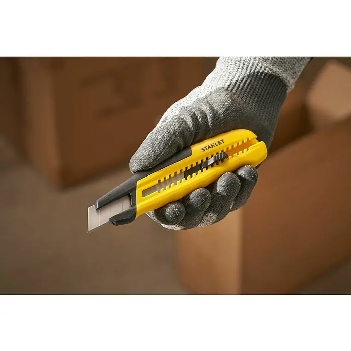 Stanley Cuchillo cúter STHT10489-0 - Plástico, Amarillo/Negro - Primer plano de un cúter Stanley sujeto en una mano con guantes protectores, ideal para abrir cajas y manualidades.