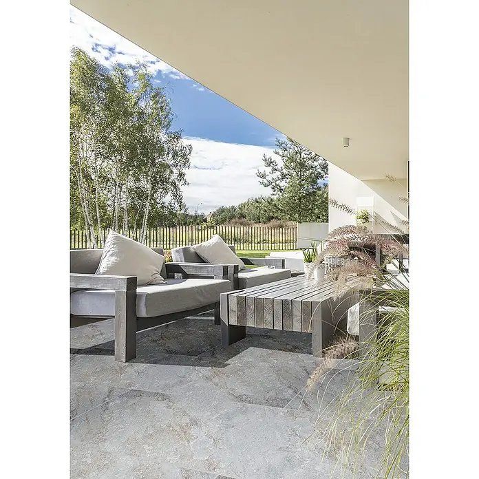 Terrassenfliese Nevada - 40 x 80 x 2 cm, Grau, Matt - Gartenmöbel-Set mit grauen Sesseln, Kissen und einem Holztisch auf einer Terrasse, die zum Entspannen einlädt. Schöne Außenanlage mit natürlichem Flair.