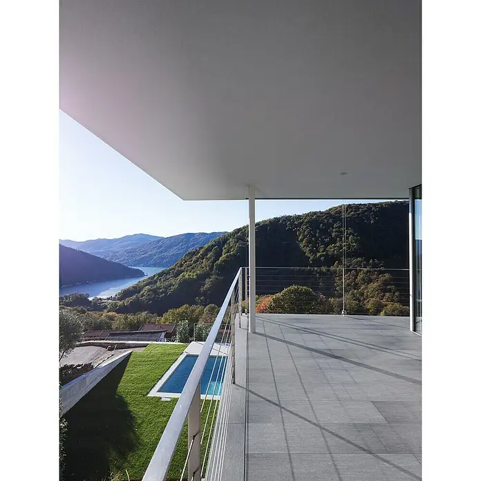 Terrassenfliese Vallis - 40 x 80 x 2 cm, Grau, Matt - Die moderne Terrasse bietet einen atemberaubenden Ausblick auf den See und die Berge, während die grauen Fliesen einen eleganten Touch verleihen.