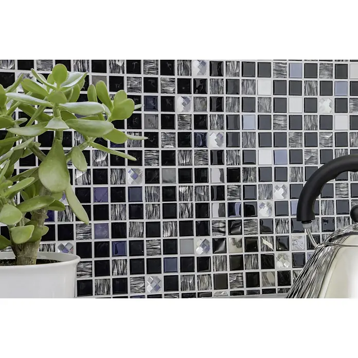 Selbstklebemosaik SAM 4CM26 - 30 x 30 cm, Mix Schwarz, Glänzend - Nahaufnahme eines Mosaikhintergrunds mit schwarzen, grauen und klaren Glasfliesen mit einer Topfpflanze und einem Teekessel im Vordergrund.