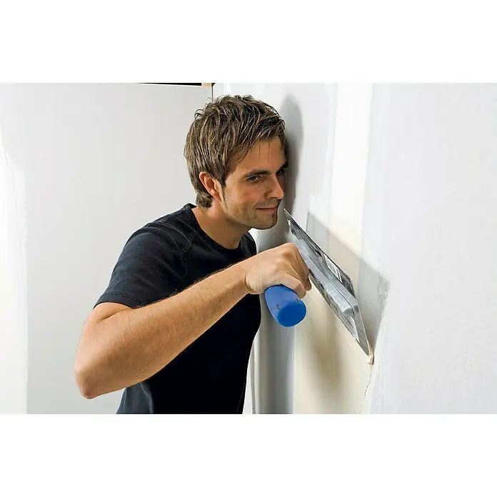 Knauf Rotband Flächenspachtel - 5 kg - Mann, der mit einer Spachtel eine Wand verputzt. Das Werkzeug verfügt über einen blauen Griff und wird für die Wandreparatur verwendet.