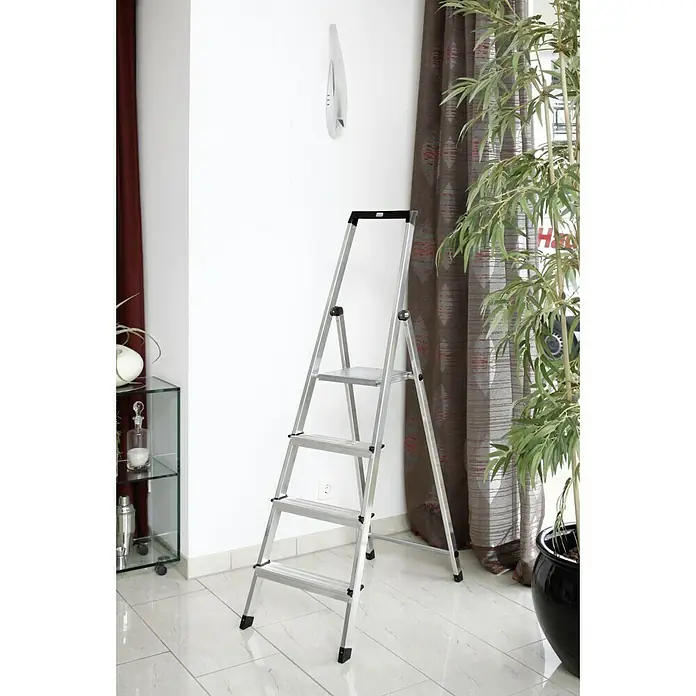 Krause Monto Stehleiter Solidy - Arbeitshöhe: 2,85 m, Anzahl Tritte: 4 Stk., Belastbarkeit: 150 kg, Aluminium - Eine silberne Haushaltsleiter mit vier Stufen steht an einer weißen Wand. Die Leiter ist zusammenklappbar und mit rutschfesten Füßen ausgestattet.