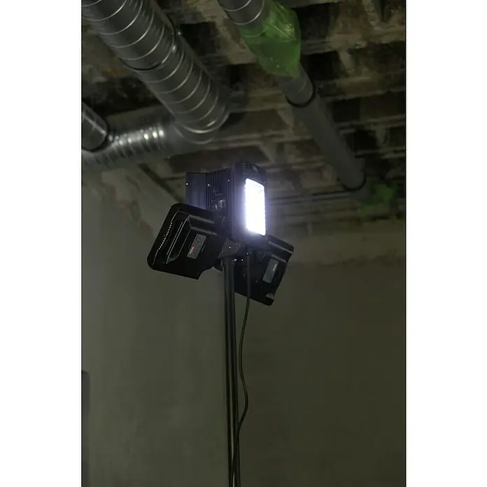 Profi Depot LED-Strahler - 8.000 lm, 6.000 K - 7.000 K, L x B x H: 1,14 x 1,32 x 2,25 m, IP54 - Aufnahme einer LED-Videoleuchte auf einem Stativ, die eine helle, fokussierte Beleuchtung in einem Raum mit sichtbaren Rohren an der Decke bietet.