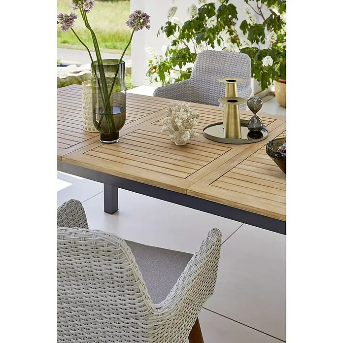 Sunfun Gartenmöbel-Set Carina/Maja - 7 -tlg., Stahl, Akazie, Kunststofffaser-Strings, Hellbraun/Grau/Anthrazit - Nahaufnahme eines Gartentisches mit Dekoration und Stühlen. Der Tisch ist aus Holz mit einem dunklen Rahmen gefertigt.
