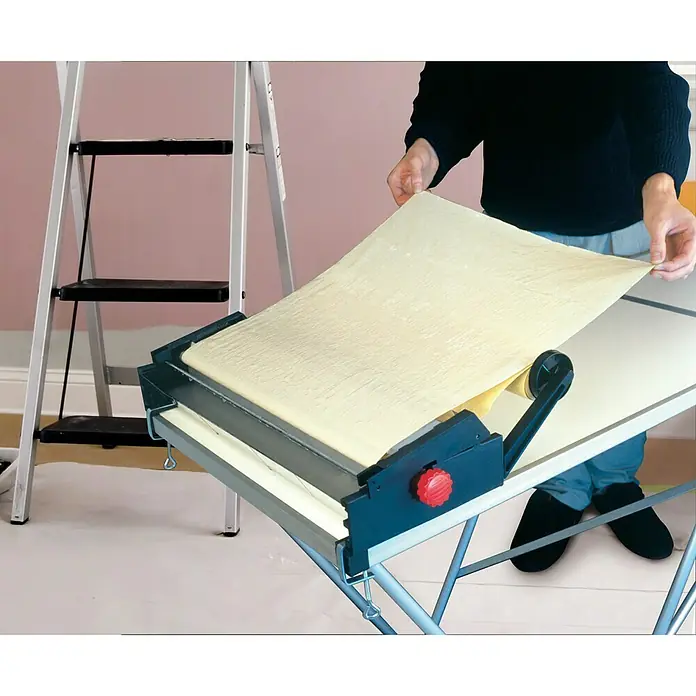 Decora Tapetenkleistergerät - Geeignet für: Euro Rollen 53 cm - Eine Tapetenkleistermaschine in Aktion, ein unverzichtbares Werkzeug für effizientes Tapezieren, neben einer Leiter platziert.