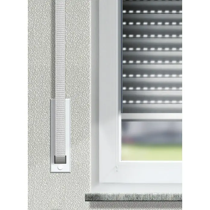 Schellenberg Cinta para persiana Mini - Gris, Largo: 6 m, Anchura de la correa: 14 mm, Polipropileno - Primer plano de una correa de persiana enrollable con enrollador en una pared blanca junto a una ventana con persianas enrollables.