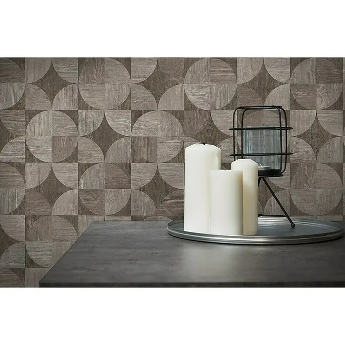 A.S. Création Metropolitan Stories Vliestapete Holzdesign - Grau/Braun, Holzoptik, 10,05 x 0,53 m - Nahaufnahme von drei weißen Kerzen und einem Kerzenhalter auf einem Tisch, vor einer braunen, gemusterten Wand.