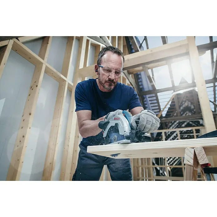 Bosch Kreissägeblatt Expert for Wood - 165 mm, Bohrung: 20 mm, Anzahl Zähne: 48 Stk. - Der Mann sägt mit einer Bosch-Kreissäge ein Brett in einer Baustelle. Schutzkleidung ist selbstverständlich.