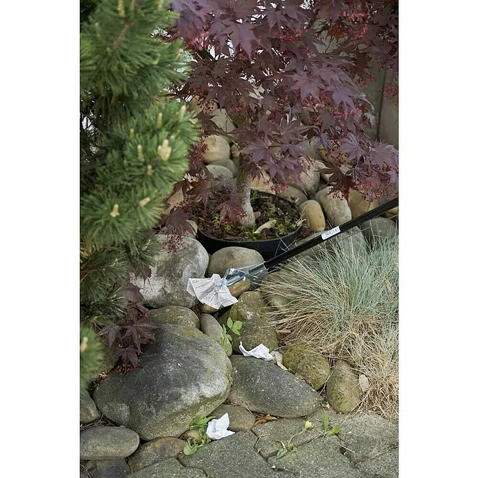 Freund Victoria Greifzange - Länge: 87 cm, Aluminium - Die Müllzange greift nach einem Papierfetzen zwischen Steinen und Pflanzen, eine praktische Hilfe für die Gartenarbeit.