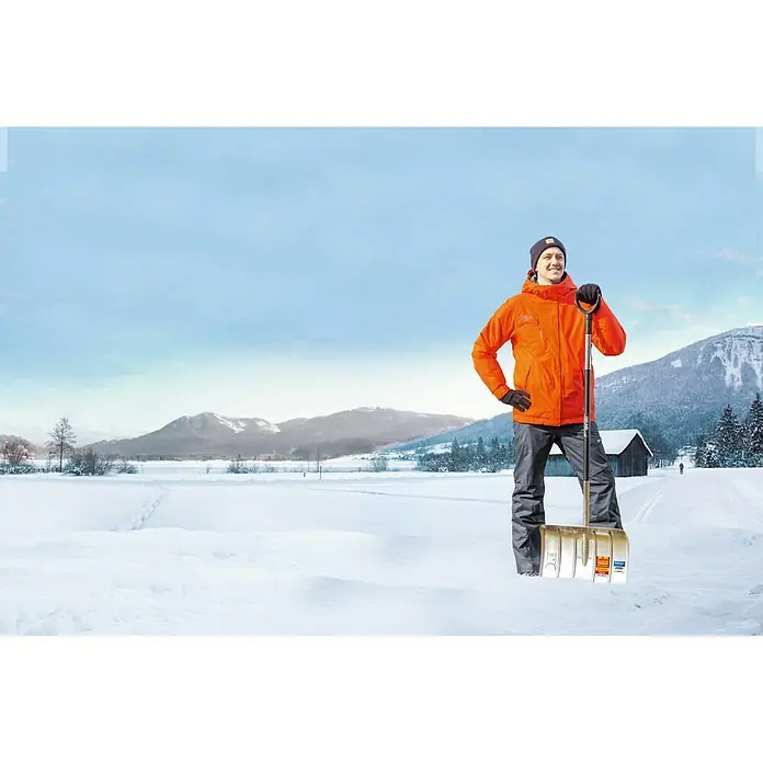 Freund Victoria Aluline Schneeschieber - Breite: 50 cm, Langstiel - Ein Mann mit einer Schneeschaufel in einer verschneiten Landschaft. Die Schaufel ist ideal zum Schneeräumen von Einfahrten und Wegen.