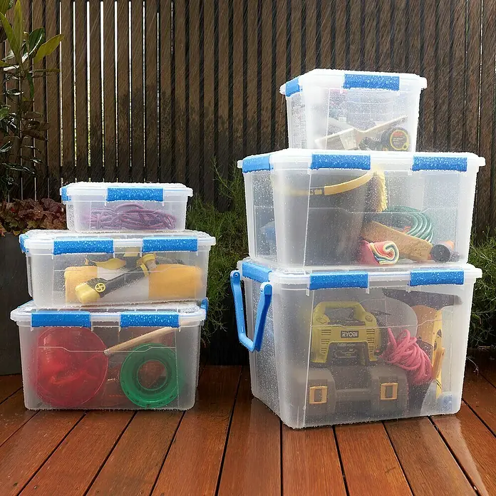 Aufbewahrungsbox Wasserdicht - L x B x H: 57,8 x 38,2 x 21,7 cm, Kunststoff, Transparent - Mehrere durchsichtige Aufbewahrungsboxen aus Kunststoff mit blauen Akzenten, gestapelt auf einer Holzterrasse im Freien.