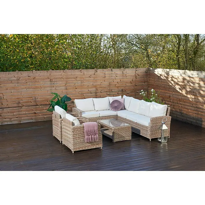 Sillón de exterior Gotland - An x Pr x Al: 80 x 81 x 77 cm, Aluminio/Ratán sintético, Beige - Un conjunto de salón de exterior de ratán con cómodos cojines blancos y una mesa de centro a juego en un patio de madera oscura.