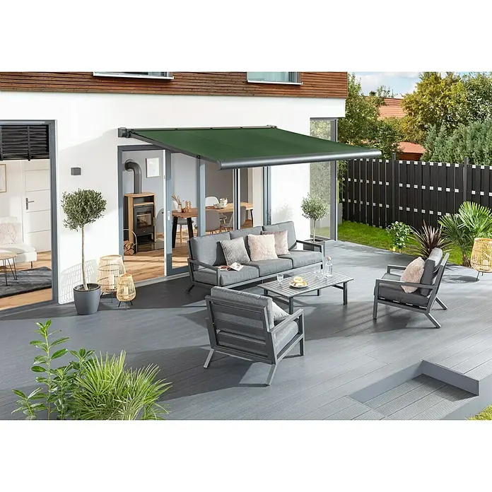 Sunfun Vollkassettenmarkise Elba - Grün, Farbe Gestell: Anthrazitgrau, Breite: 4 m, Ausfall: 3,5 m - Moderne Terrassenüberdachung mit grüner Markise und grauen Gartenmöbeln auf einer grauen Holzterrasse, die einen stilvollen Außenbereich schafft.