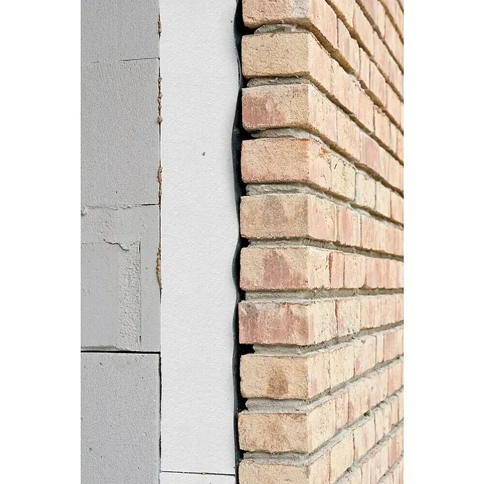 Knauf Placa de poliestireno expandido EPS - 1 m x 0,6 m x 1 cm, Plástico - Primer plano de una pared de ladrillo con aislamiento. La fachada de ladrillo rojo está revestida con una capa aislante blanca.