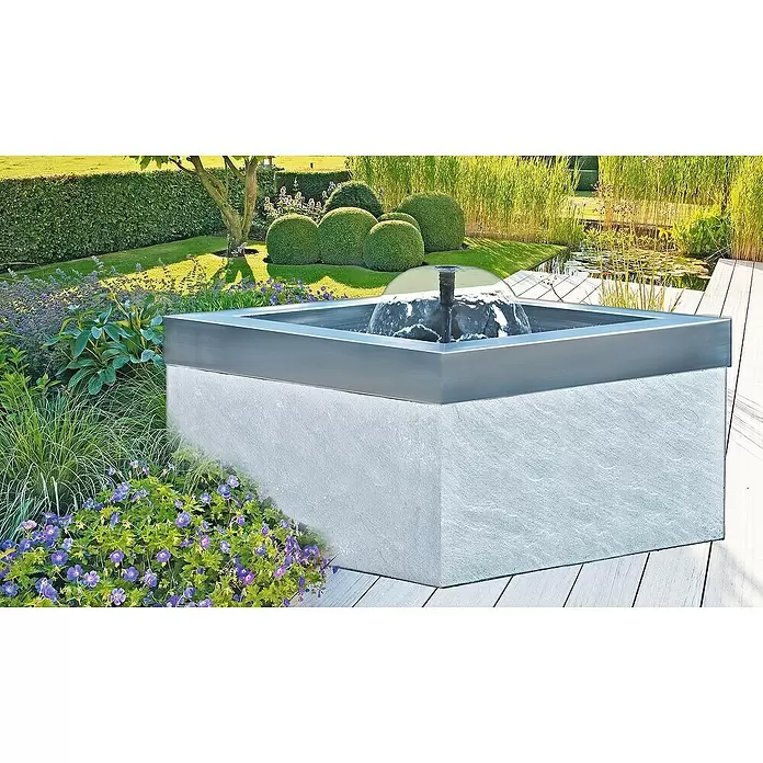 Heissner Teichschale - 79 x 79 x 45 cm, Fassungsvermögen: 200 l - Ein quadratisches Wasserspiel mit hellgrauem Steinsockel und dunkelgrauem Metallrand, Wasser sprudelt. Auf Holzterrasse in einem üppigen Garten.