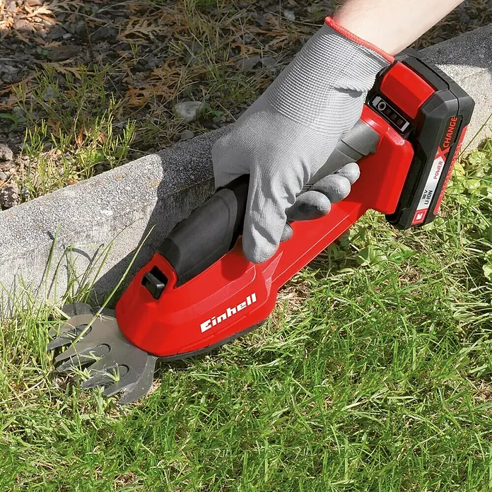 Einhell Power X-Change 18V Akku-Gras- & Strauchschere GC-CG 18 Li-Solo - 18 V, Li-Ionen, Ohne Akku, 100 mm - Akkurasentrimmer im Einsatz mit rotem Gehäuse und grauem Handschuh. Ideal zum Kantenschneiden und für kleine Flächen.