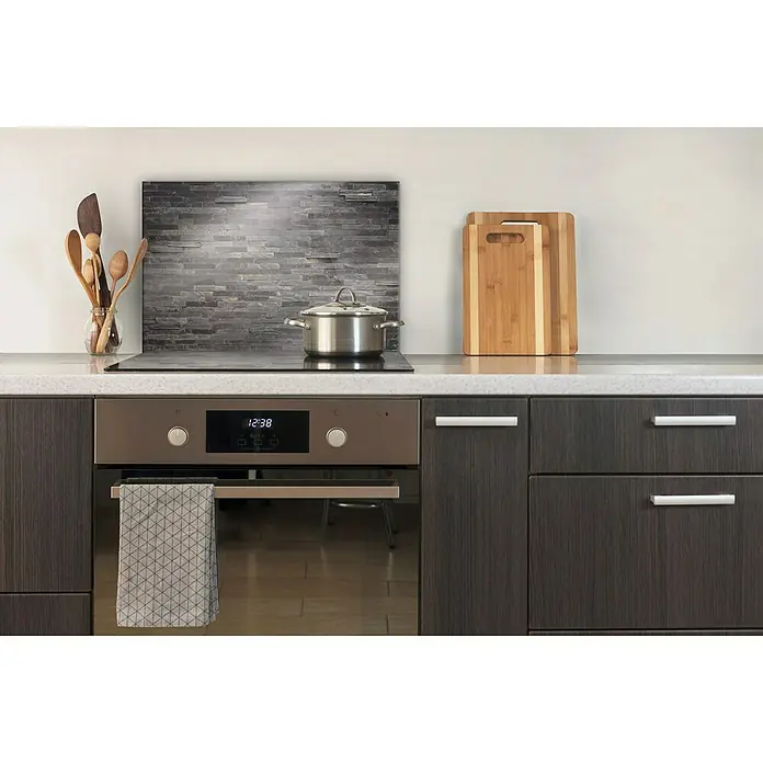 CUCINE Küchenrückwand - Stonehenge, 60 x 40 cm, Stärke: 6 mm, Einscheibensicherheitsglas (ESG) - Küchenansicht mit modernem Herd und Kochfeld, darüber ein Topf. Holzutensilien, Schneidebretter und ein Geschirrtuch ergänzen das Bild.