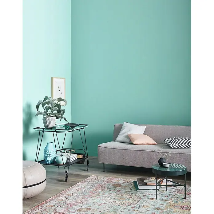 SCHÖNER WOHNEN-Farbe Wandfarbe Trendfarbe - Frozen, Matt, 1 l, Konservierungsmittelfrei - Ein stilvolles Wohnzimmer mit einem grauen Sofa, einem eleganten Beistelltisch und einem bunten Teppich, das einladend und modern wirkt.
